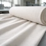 A detailed view of jersey knit fabric on a production table, displaying its unique loop construction and soft, flexible surface, ideal for t-shirts.