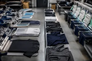 Home 41 A high-resolution overview of a gymwear manufacturer’s production floor with custom printing and embroidery equipment, representing modern activewear branding methods.